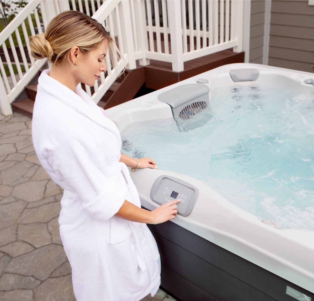 A woman in a white robe is adjusting her hot tub.